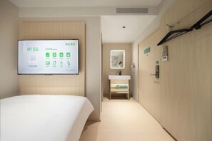A hotel room with a bed, a wall-mounted TV displaying room information, a bathroom with a sink and mirror, and a hallway with a coat rack. - Hi Inn (Beijing Tiananmen National Grand Theater) (Beijing)