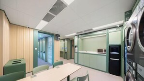 A room with a table and chairs, a washing machine, and a small kitchenette area. - Hi Inn (Beijing Tiananmen National Grand Theater) (Beijing)