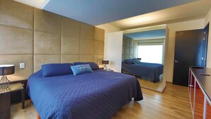 Une chambre à coucher moderne avec un grand lit, une table de chevet, une lampe et une armoire.