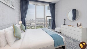 A modern hotel room with a large bed, a dresser, a round mirror, and a view of the city through large windows. - Vogue| Al Wasl 1 Residence near World Trade Centre (Dubai)