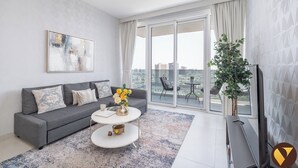 A modern living room with a grey sofa, a white coffee table, and a large window with a city view. - Vogue| Al Wasl 1 Residence near World Trade Centre (Dubai)