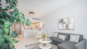 A modern living room with a grey sofa, a white coffee table, and a dining area in the background. - Vogue| Al Wasl 1 Residence near World Trade Centre (Dubai)