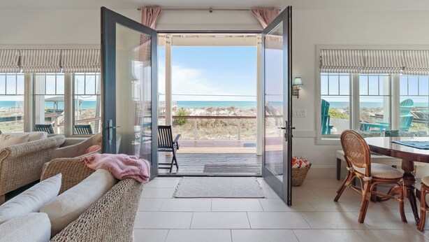 Una habitación con vistas a la playa, un comedor con sillas, un sofá y una mesa.
