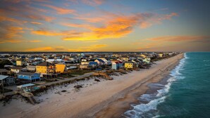 Un pueblo costero con playa y vista al océano, con casas coloridas y un cielo despejado.