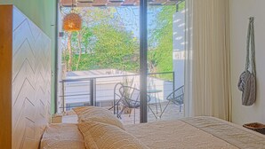 Ein Schlafzimmer mit Bett, Deckenventilator und Blick ins Freie.