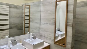 A modern bathroom with a large mirror, two sinks, and a wooden vanity.
