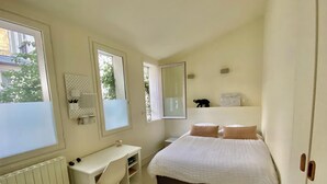 A bedroom with a bed, a desk, and a radiator.