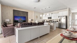 Ein modernes Wohnzimmer mit Sofa, Fernseher und Essbereich mit gedecktem Tisch.