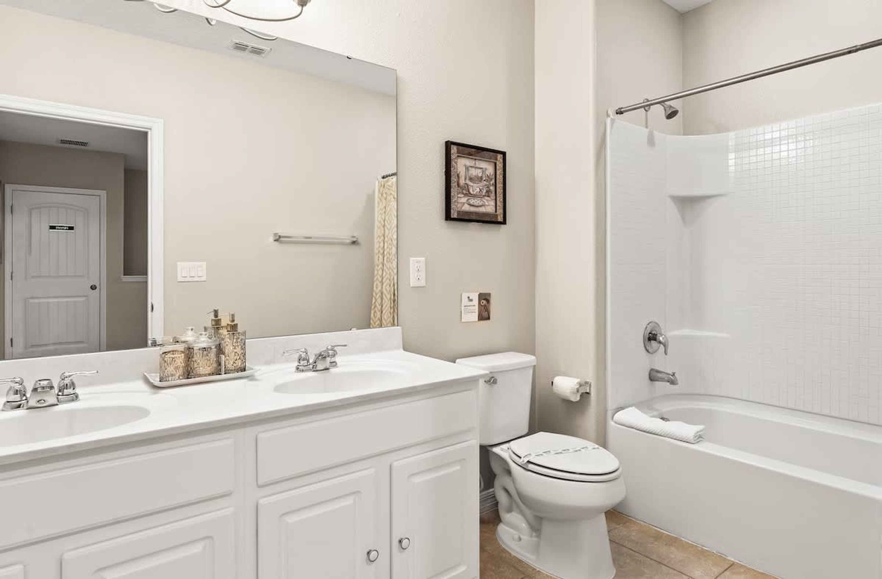 A bathroom with a double sink vanity, a toilet, and a walk-in shower.