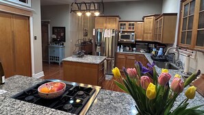 A kitchen with granite countertops, stainless steel appliances, wooden cabinets, and a central island.