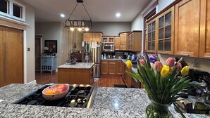 A kitchen with granite countertops, stainless steel appliances, wooden cabinets, and a central island.