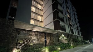 Een modern gebouw met een stenen gevel, een metalen hekwerk en een goed verlicht pad.