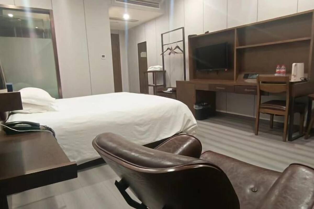 A hotel room with a bed, a desk, a chair, a television, and a wardrobe.