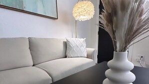 A modern living room with a sofa, a white vase with dried pampas grass, and a floor lamp.
