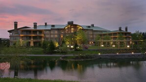 A large, multi-story building with a prominent central structure, surrounded by a landscaped garden and a body of water. - The Lodge at Turning Stone Resort Casino (Verona)