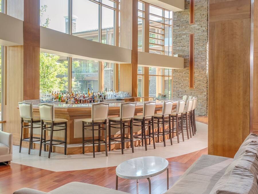 Un bar spacieux et moderne, doté de hauts plafonds et de grandes fenêtres, offrant une vue sur l’extérieur.