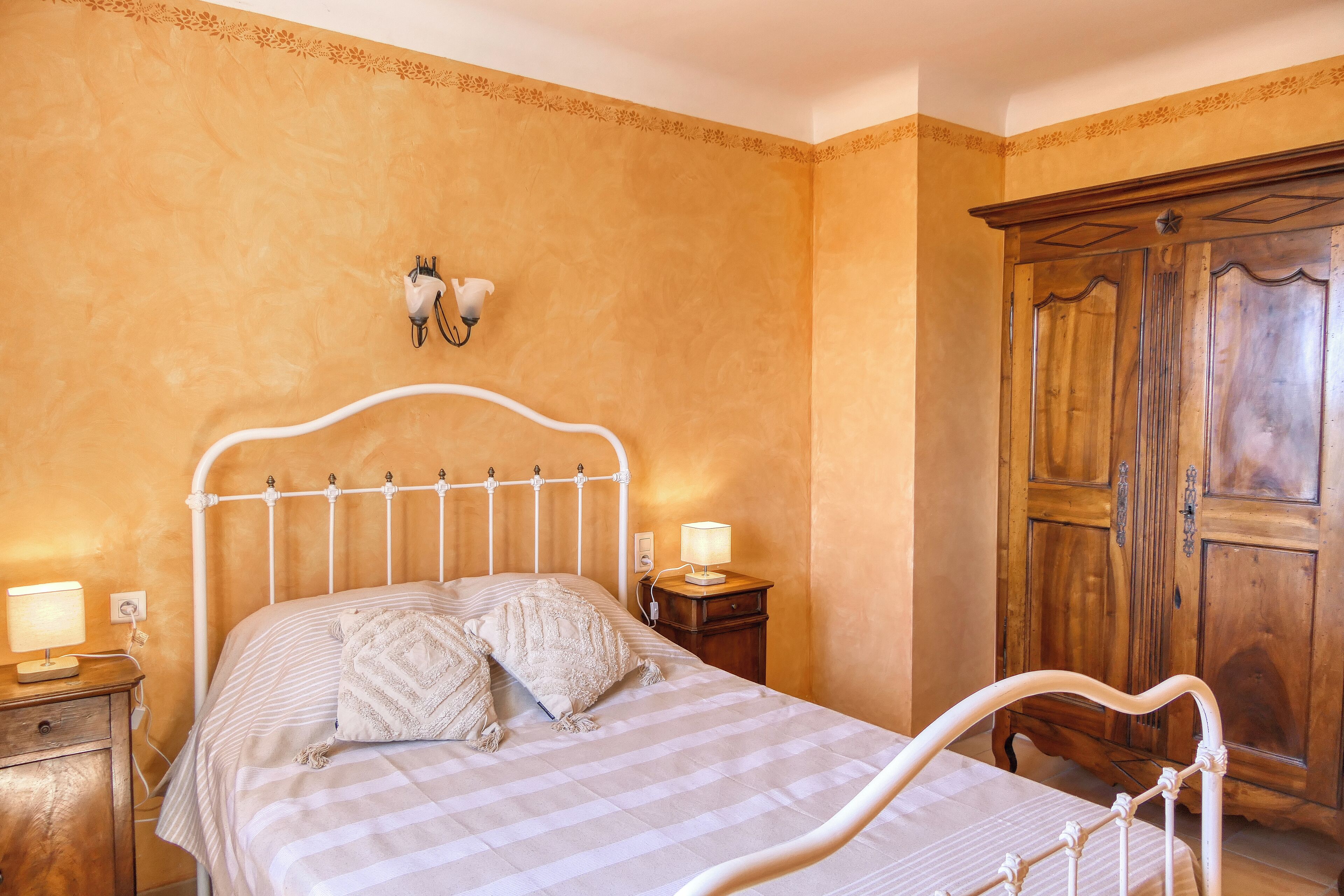 Una camera da letto con un letto, lampade sui comodini, un armadio in legno e un punto luce a parete.