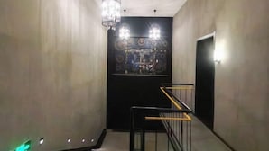 A narrow hallway with a staircase, a chandelier, and a door with a decorative panel. - Pebble Hotel (Taiyuan Hengshan Road Taigang East Gate) (Taiyuan)
