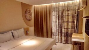 A hotel room with a bed, a bedside table, a wall-mounted TV, and a window with curtains. - Pebble Hotel (Taiyuan Hengshan Road Taigang East Gate) (Taiyuan)