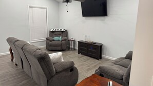 A modern living room with a grey sofa, a recliner, a wooden coffee table, and a TV mounted on the wall. - Kentucky Lake Retreat / 1 Mile to Jonathan Creek / Boat Parking (Benton)