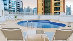 Ein Pool auf dem Dach mit Blick auf die Stadt, umgeben von weißen Geländern und ausgestattet mit Liegestühlen und Tischen.