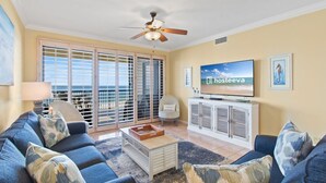 Una sala de estar con sofá, mesa de centro, televisor y un balcón con vistas.