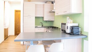 A compact kitchen with a central island, a microwave, and a coffee machine.