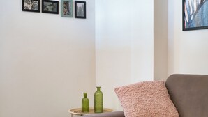 A room with a brown sofa, a green vase, and a pink pillow.