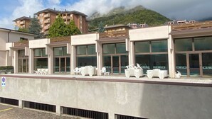 Hotel met een modern design, met grote ramen en een plat dak. Er zijn buiten zitgedeeltes met stoelen en tafels.