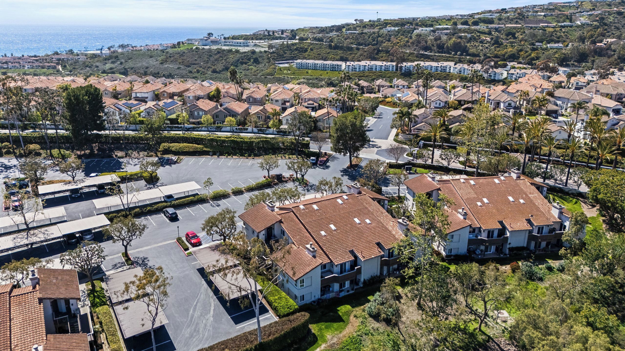 A residential area with houses, a parking lot, and a view of the ocean.
