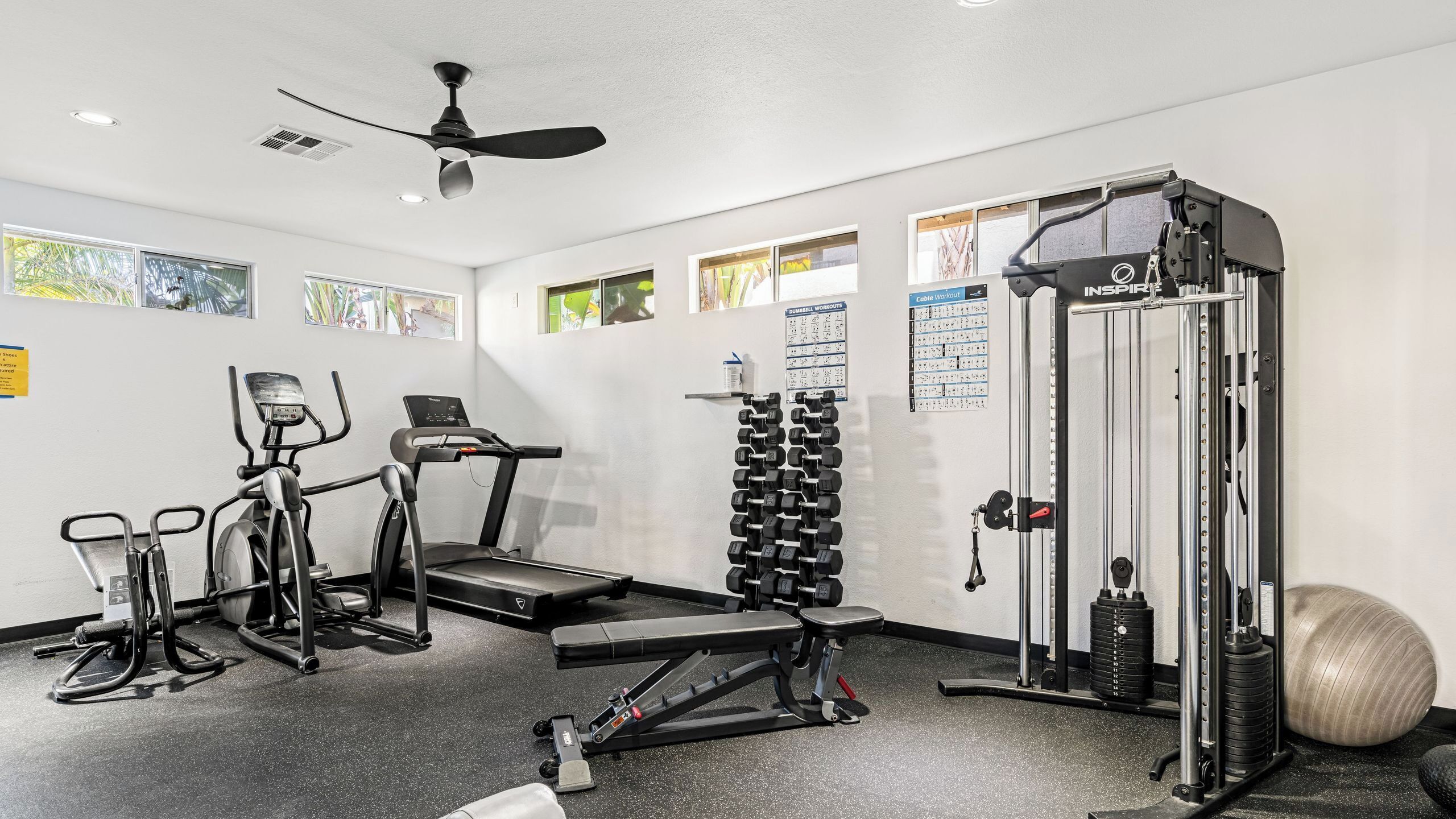Ein Fitnessraum mit Laufbändern, Kabelzugmaschine, Kurzhanteln und Medizinball.