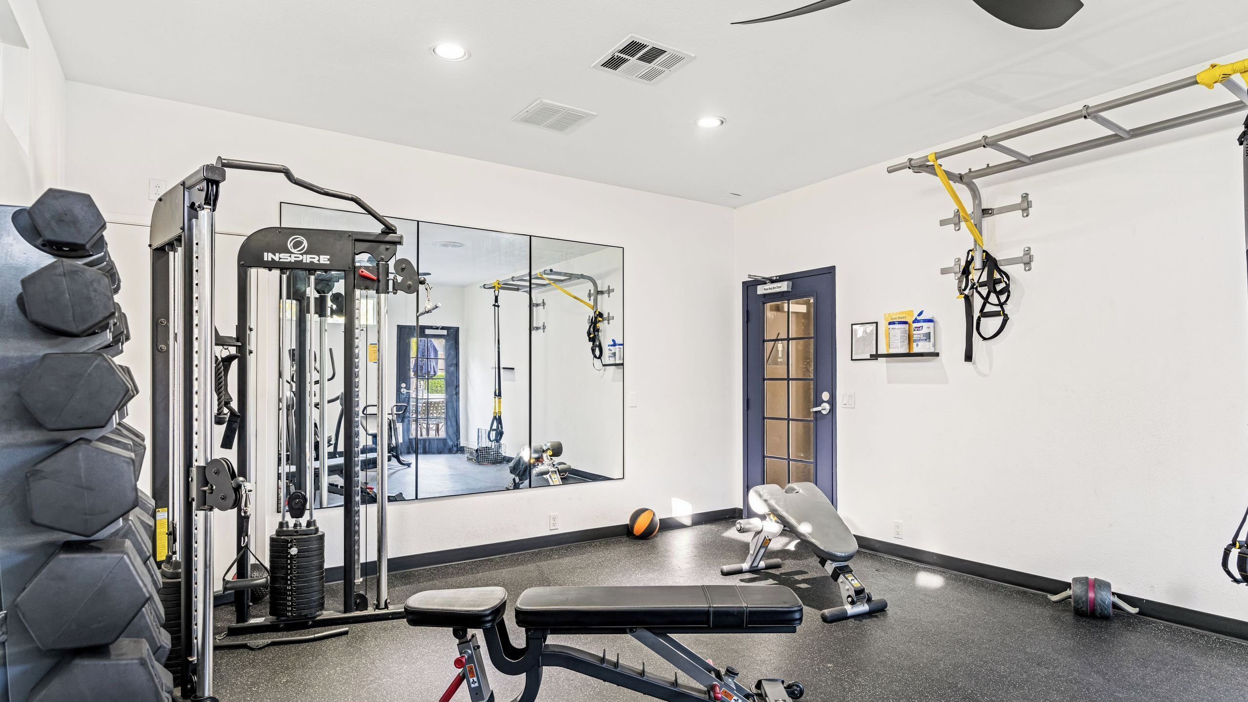 A gym with exercise equipment, a bench, and a mirror.