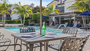 Un espace aménagé au bord de la piscine, avec des tables, des chaises et des parasols.