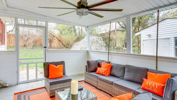 A covered patio area with a ceiling fan, wicker furniture, and a glass coffee table.