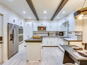 A modern kitchen with white cabinetry, stainless steel appliances, and a central island.