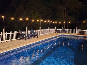 A swimming pool with a white fence and string lights, surrounded by chairs and a deck. - 4BR/2BA Home with Private Pool – 5 Min to Bucknell University – Sleeps 12 (Lewisburg)