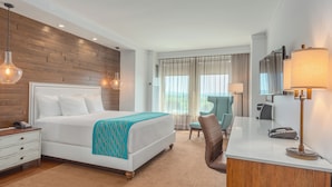 A hotel room with a wooden accent wall, a bed with white bedding, a desk with a lamp, and a chair. - The Tower at Turning Stone Resort Casino (Verona)