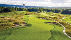 A golf course with a winding path, sand bunkers, and a distant building. - The Tower at Turning Stone Resort Casino (Verona)