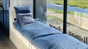 Une chambre moderne avec une grande fenêtre, un lit avec une literie bleue et un luminaire suspendu.