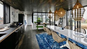 Une cuisine moderne dotée d’un grand îlot central, d’un plafond en bois foncé et de luminaires suspendus.