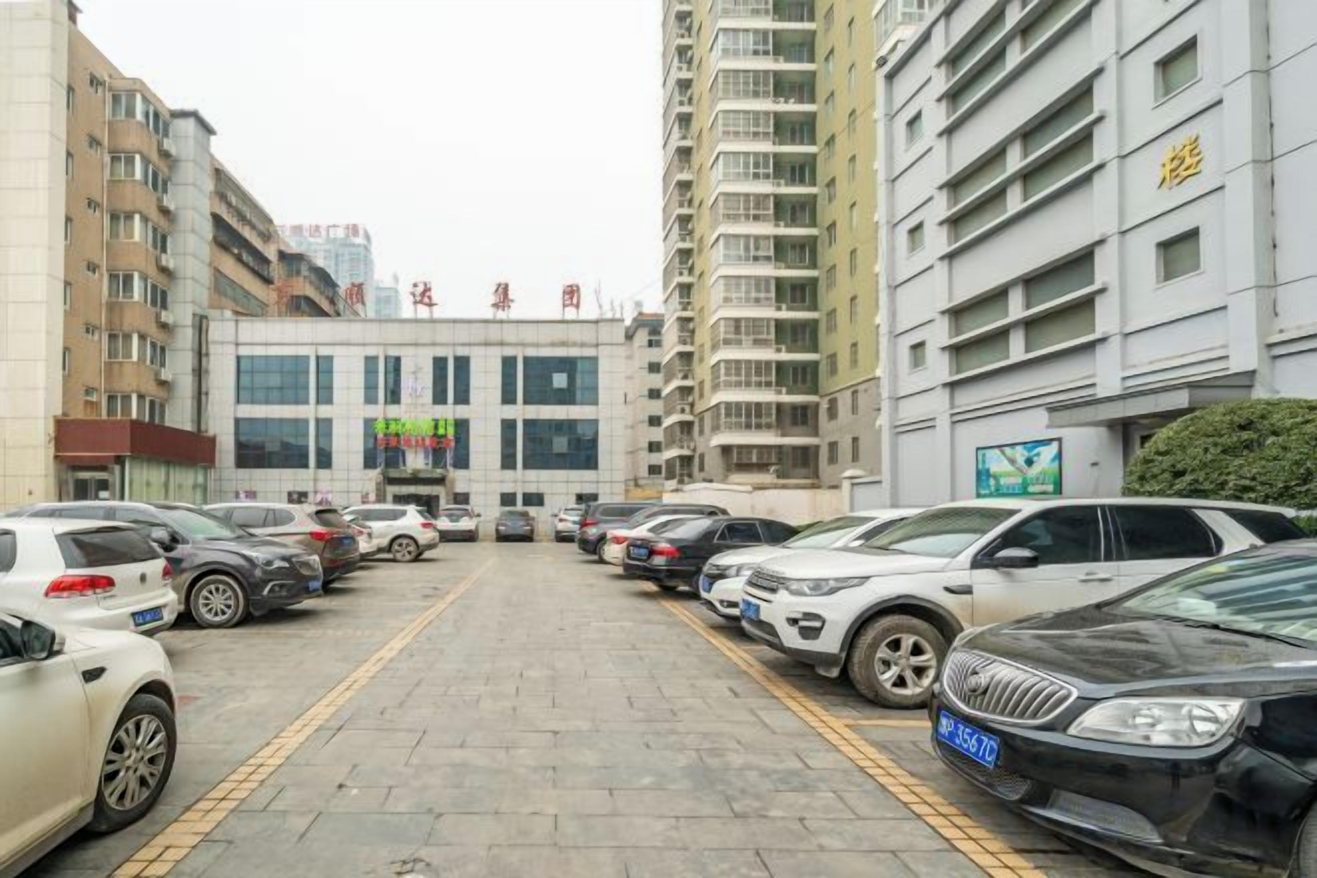 Un estacionamiento con varios coches aparcados frente a un edificio con un cartel que dice 'Hotel'.