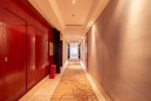 A hotel corridor with a red door, a patterned carpet, and a light-colored wall. - Zhoukou Hotel (Zhoukou Wanshunda Department Store) (Zhoukou)