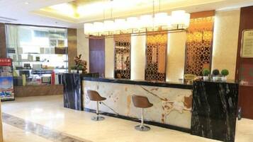 A hotel reception area with a marble counter, two bar stools, and a decorative wall with patterned panels.