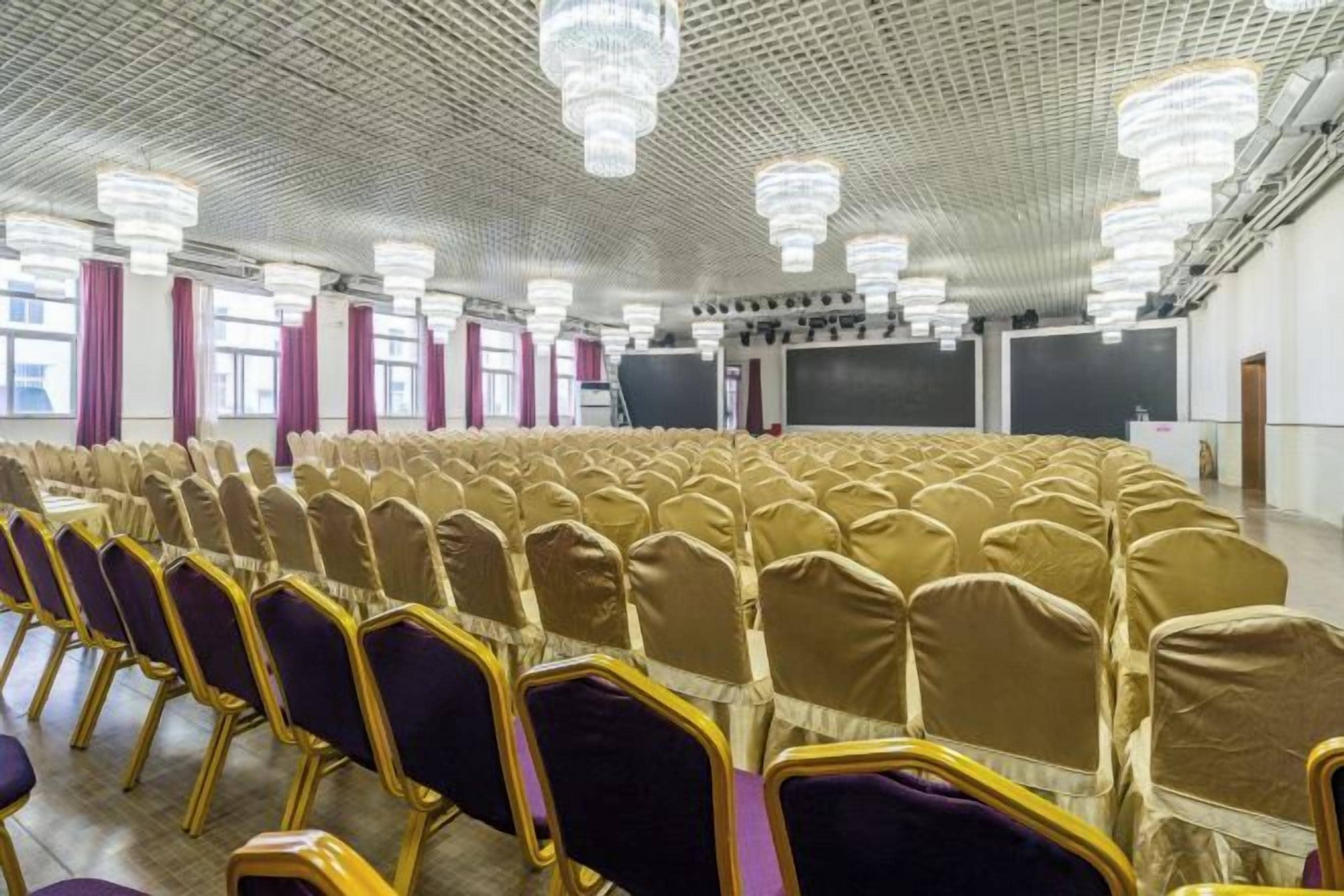 Un salón de conferencias con hileras de sillas, un escenario y una pantalla grande.