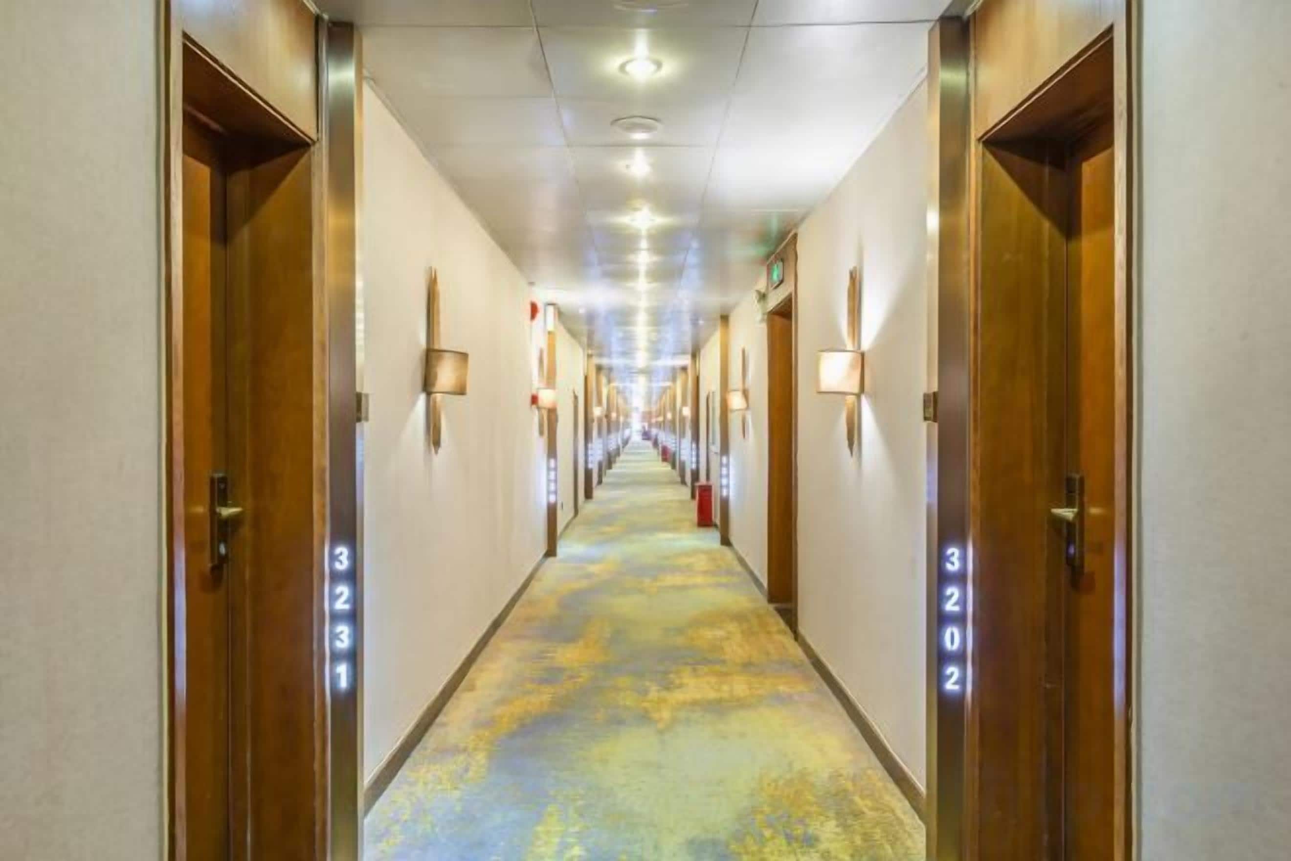 Een hotelgang met deuren met de nummers 3231 en 3222, met een vloerbedekking en verlichting van bovenaf.