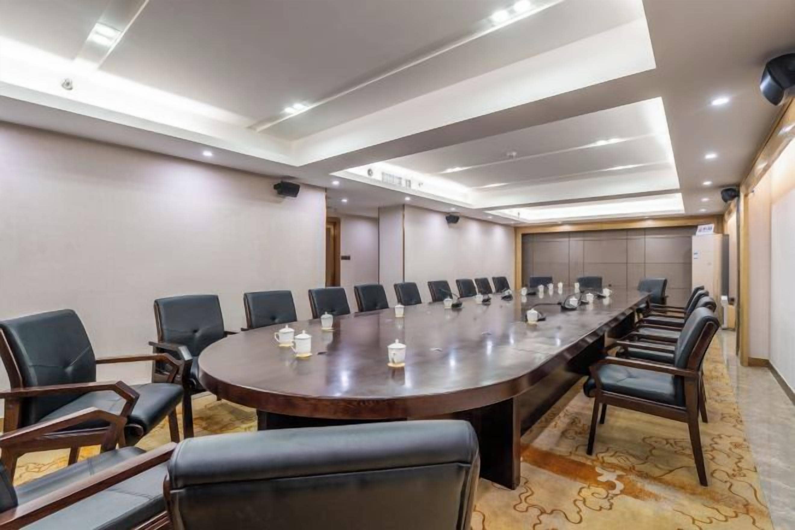 Un salón de conferencias con una gran mesa ovalada, varias sillas y piso alfombrado.