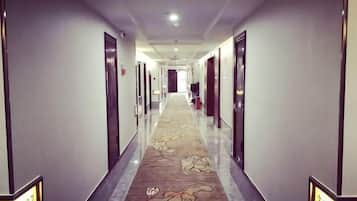 A hotel hallway with doors on both sides, a carpeted floor, and a number sign on the wall.
