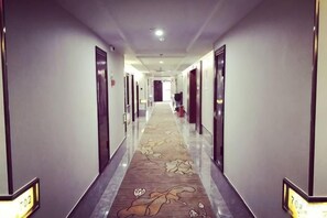 A hotel hallway with doors on both sides, a carpeted floor, and a number sign on the wall. - Zhoukou Hotel (Zhoukou Wanshunda Department Store) (Zhoukou)