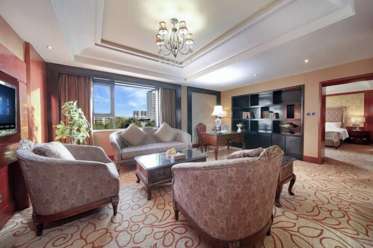 A spacious living room with a sofa, armchairs, a coffee table, and a bookshelf.