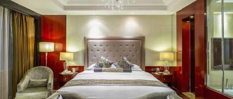 Habitación de hotel con una cama grande, dos mesitas de noche, un candelabro, una silla y un espejo amplio.